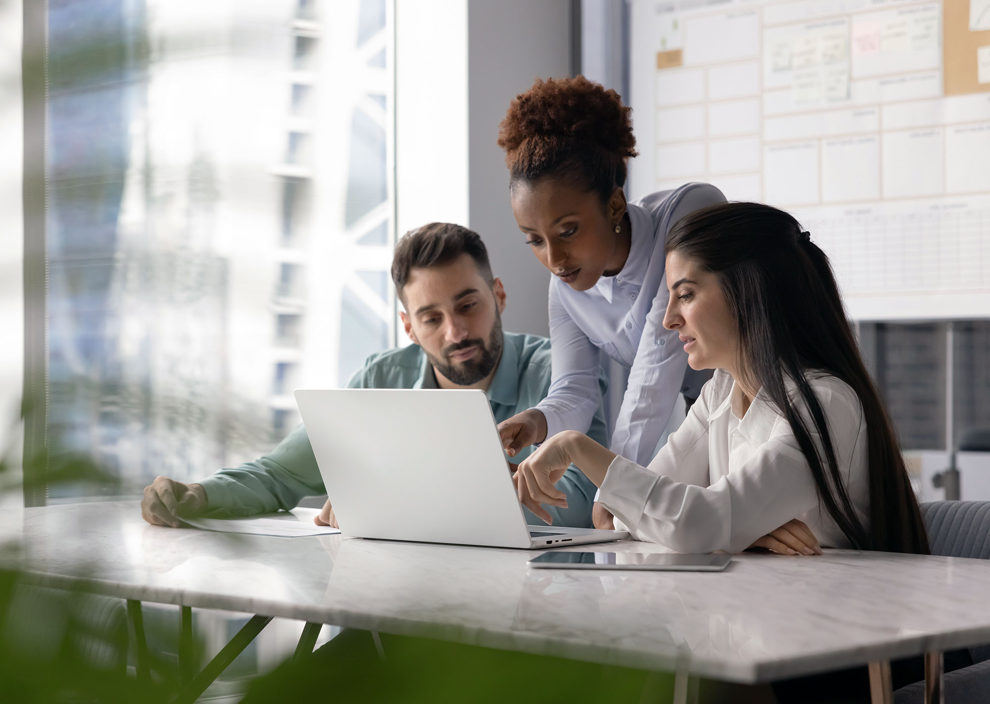 multi-ethnic group of college marketing employees discussing a website around a single laptop