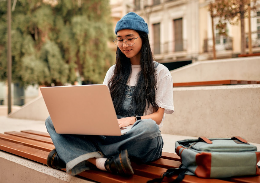 student researching universities on her laptop outside
