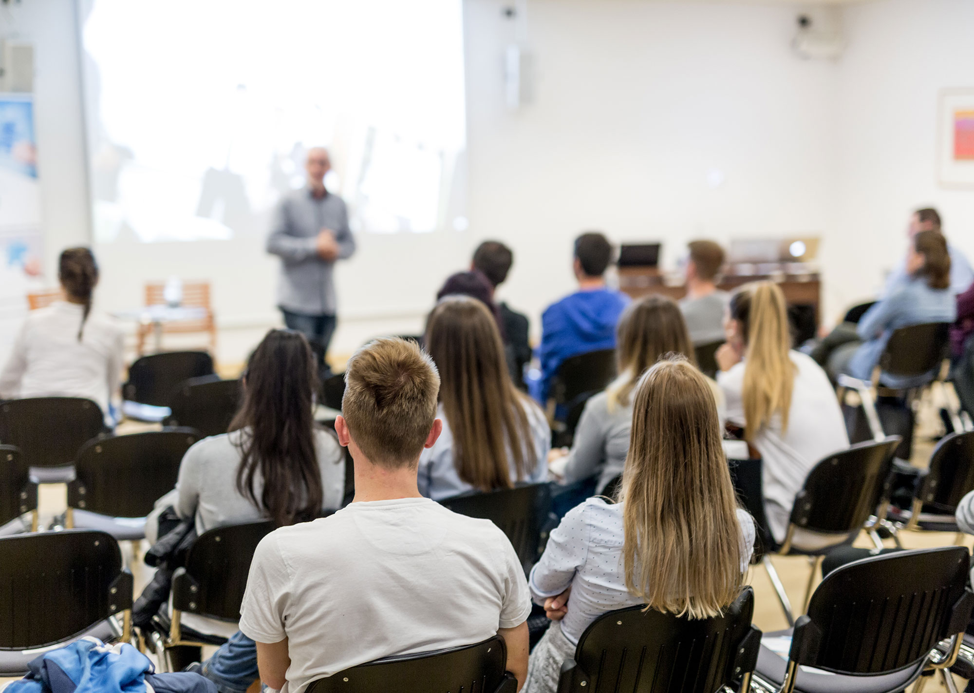 professor speaking to students in lecture hall with some empty seats enrollment strategies can fill