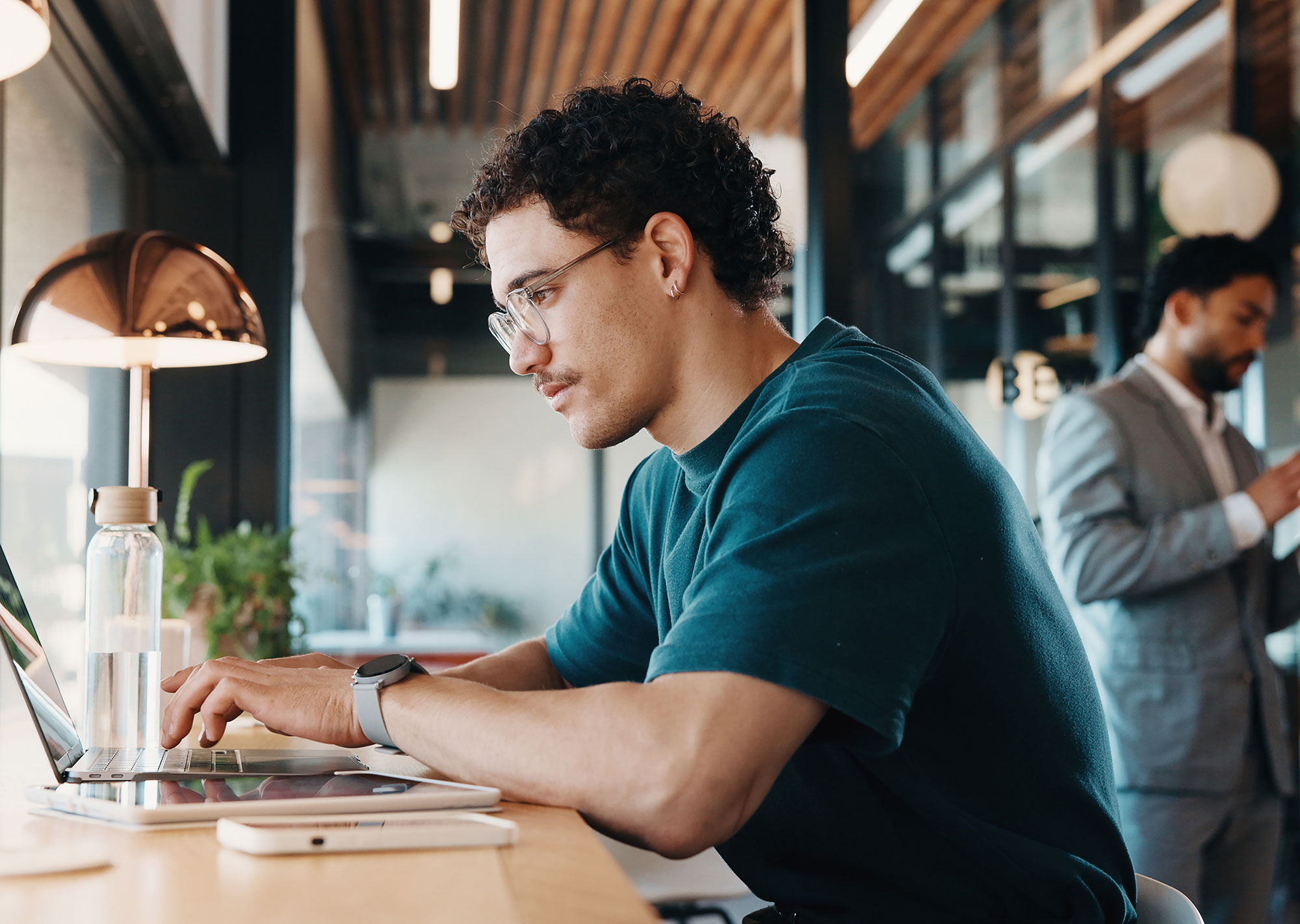 web designer building on laptop with coworker in the background